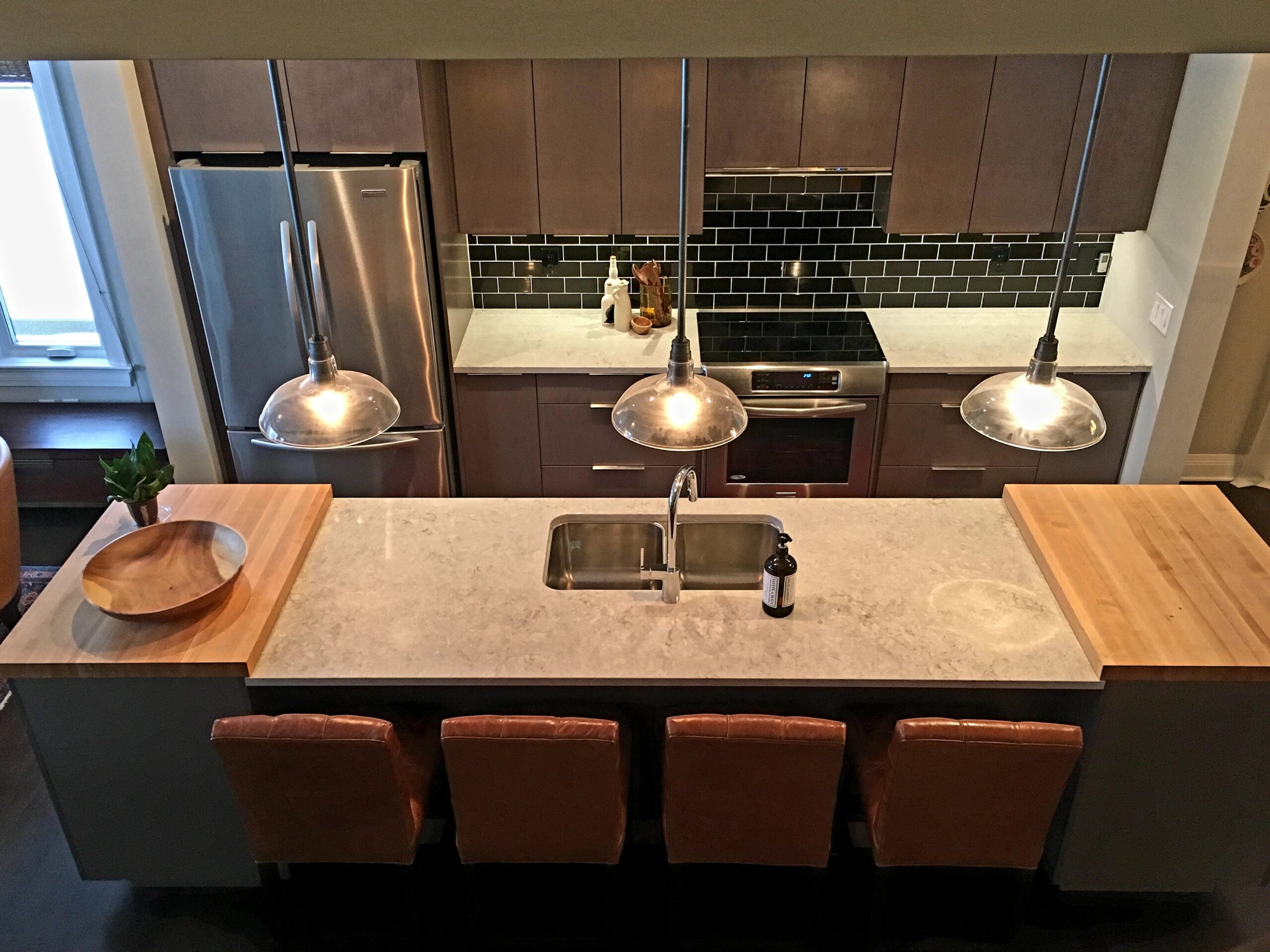 A modern kitchen in Denver with pendant lights over an island, recessed ceiling lights, and under-cabinet LED lighting.