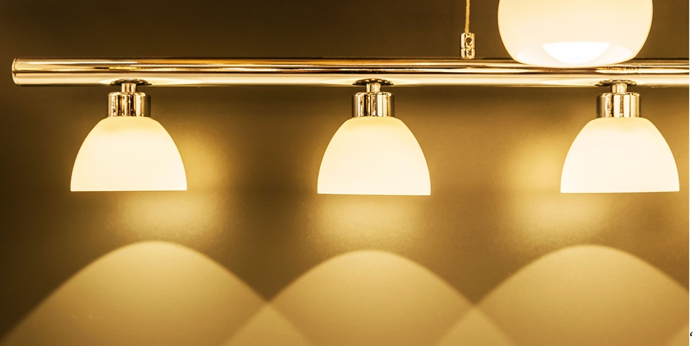 Elegant triple dome wall light fixture with frosted glass shades and chrome finish, casting warm ambient glow, ideal for modern interiors, bathroom vanity, or hallway lighting design.