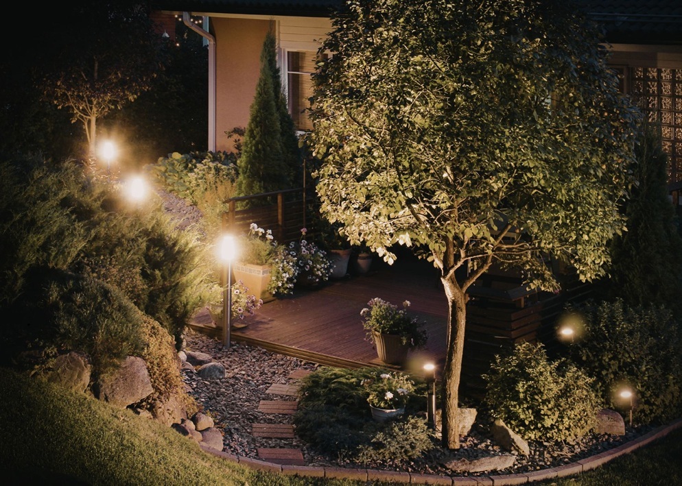 Warm garden lights around a deck illustrating landscape light maintenance and proper landscape lighting care.